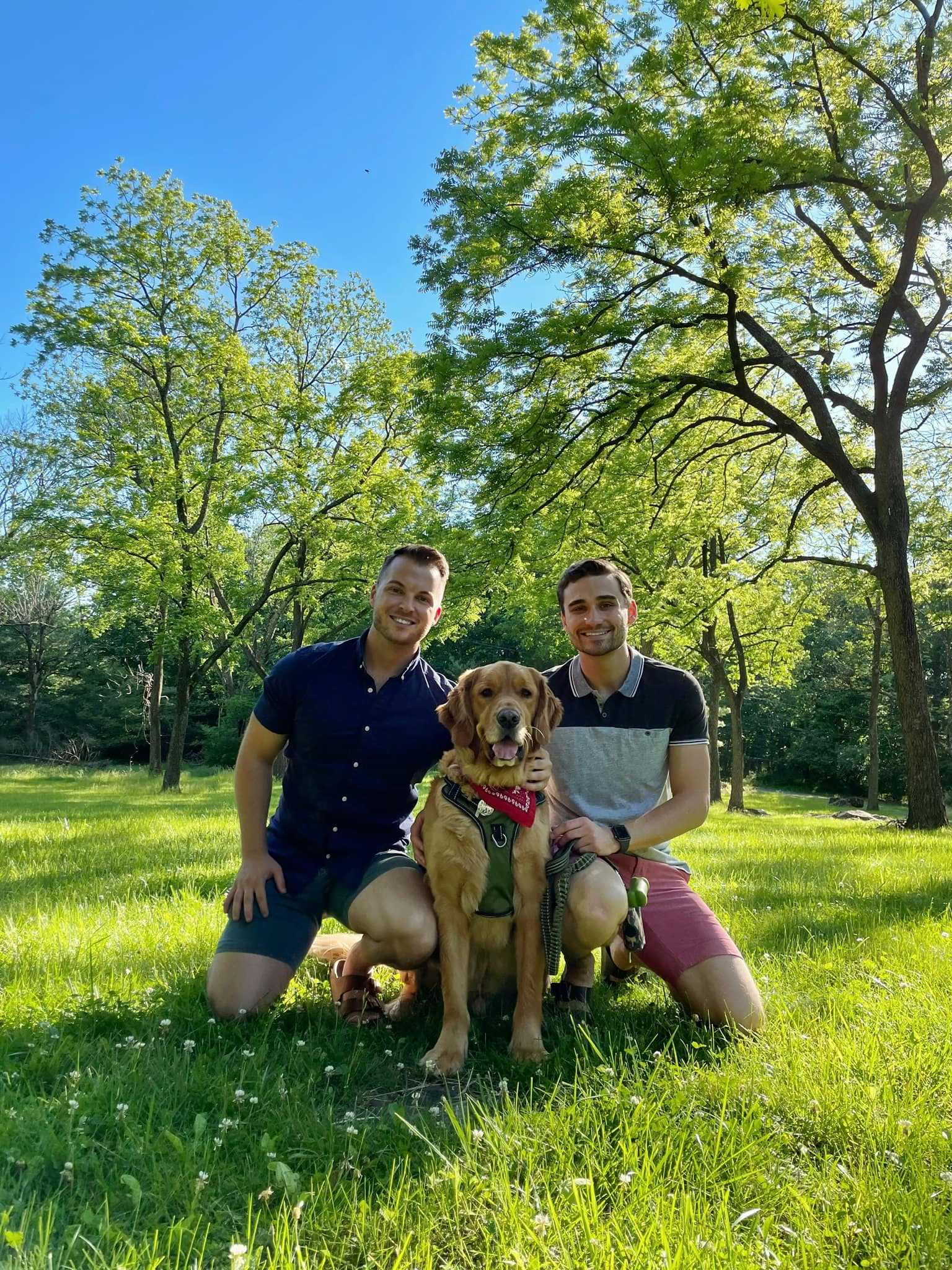 Two men sitting on grass with a dog